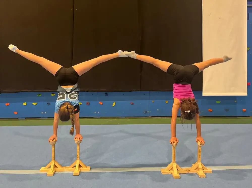 Dos gimnastas haciendo el pino en paralelas de entrenamiento